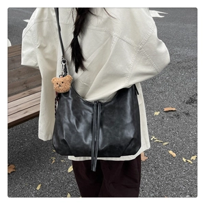 Vue détaillée d'un sac Hobo noir avec de longues franges et un porte-clé ours