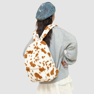 Detail view of cow print plush backpack with soft fuzzy texture and zippered pocket
