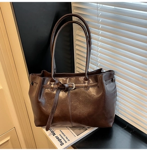 Détail d'un cabas en similicuir marron foncé brillant avec boucle métallique sur un rebord