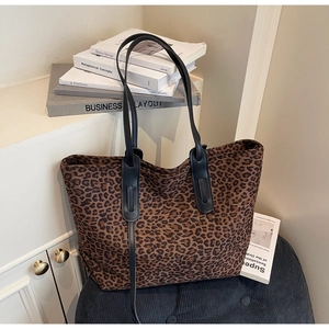 Vue détaillée du sac cabas en daim imprimé léopard avec des anses en cuir noir sur chaise