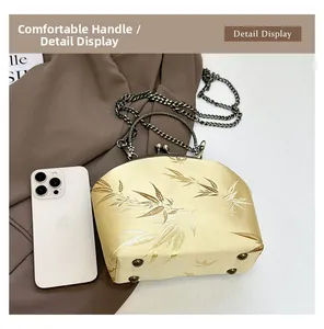 Detail view of champagne satin handbag with gold bamboo embroidery and metal chain strap