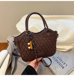 Close-up of deep brown bucket bag with woven texture and decorative wooden beads