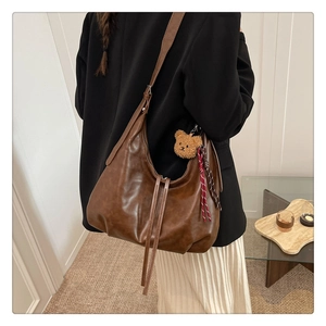 Grand sac porté épaule marron rétro avec charm ours porté par un mannequin au bureau
