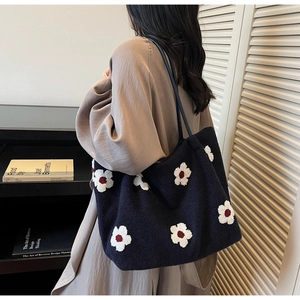 Detail of navy blue tote bag with white floral pattern on a female model's shoulder