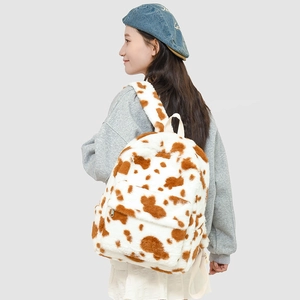 Detail of plush backpack featuring cow print pattern and adjustable fuzzy straps