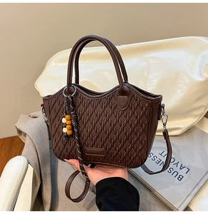 Detail of dark brown woven tote bag with wooden bead charm and detachable strap