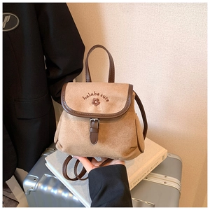 Detail of vintage bucket backpack with flower embroidery and leather contrast on a suitcase