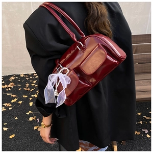 Detail of burgundy patent leather tote bag with lace bow and pearl pendant charm