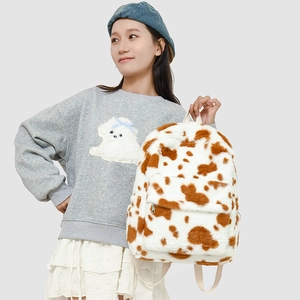 Detail view of plush cow print backpack on model showing fuzzy texture and straps