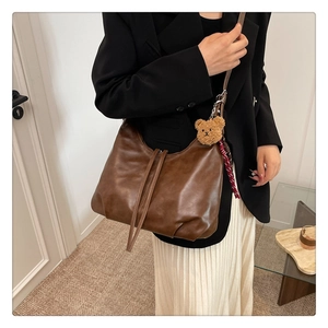 Détail du sac hobo en cuir mat marron foncé avec un ours en peluche et un foulard