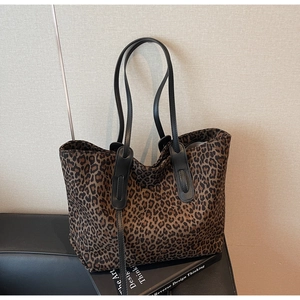 Détail du cabas imprimé léopard avec des poignées en cuir noir sur un canapé