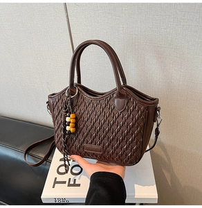 Detail of dark brown woven bucket bag with wood bead tassel on a fashion book background