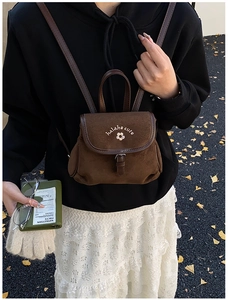 Macro detail of brown suede mini backpack featuring white flower embroidery and leather buckle