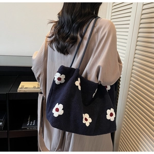 Detailed close-up of dark blue floral tote bag with soft faux fur texture and black handles