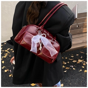 Detail of burgundy glossy PU shoulder bag with pearl pendant and bow decoration