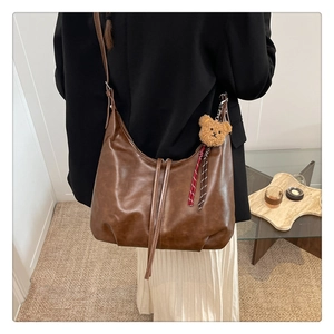 Détail d'un sac cabas vintage marron avec un ourson en peluche sur cuir souple
