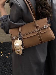 Sac Boston marron en laine avec pendentif ours, porté par un mannequin en décor d'automne