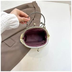 Detail of vintage kiss-lock bag showing bronze metal frame and burgundy lining