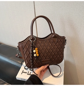 Detailed view of brown woven texture bucket bag with wooden bead charm and round handles
