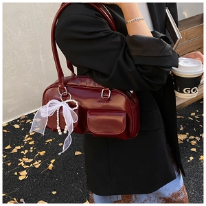 Detail of dark red Boston bag with pearl lace charm and dual front pockets