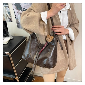 Détail du sac hobo marron foncé avec fermeture éclair à franges et charm ours en peluche