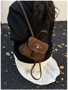 Detail of brown suede backpack featuring floral embroidery and a premium leather strap