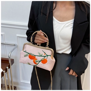 Gros plan du sac en soie rose avec broderie traditionnelle et bandoulière en chaîne dorée