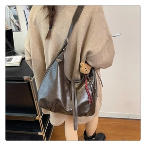 Détail du grand sac hobo marron foncé avec pendentif ours dans un décor de bureau moderne