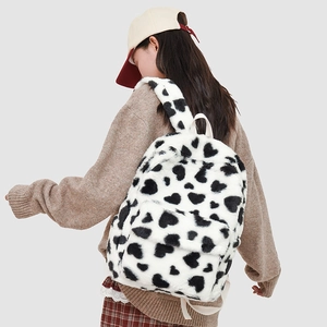 Detail of plush white backpack with black heart patterns and soft furry straps