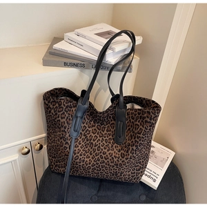 Détail du sac cabas léopard en daim avec anses en cuir sur un tabouret vintage