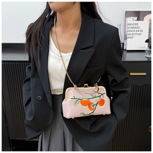 Broderie détaillée d'orange et de feuilles vertes sur un sac en soie rose à fermoir
