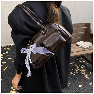 Macro view of dark brown retro underarm bag with glossy texture and pearl chain detail