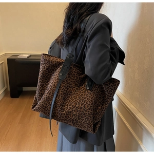 Détail du sac cabas léopard avec bandoulière en cuir noir sur un banc gris
