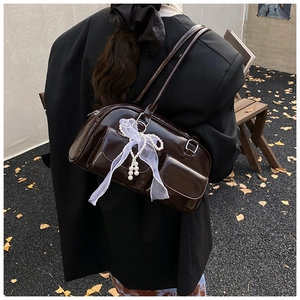 Brown faux leather underarm bag with white mesh bow and pearl charms worn by model