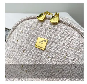 Dettaglio del tessuto tweed di qualità con fili dorati e targhetta del marchio in metallo oro