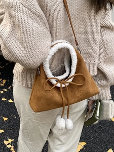 Sac à bandoulière en daim marron avec bordure en peau de mouton blanche et nœud à pompons