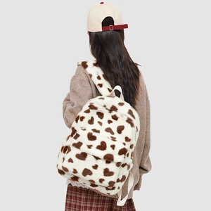 Detail view of white fuzzy backpack with brown heart patterns worn on model back