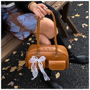 Brown faux leather Boston bag featuring front flap pockets and decorative lace bow charm