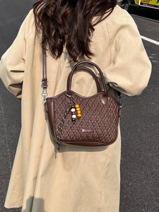Dark brown woven bucket bag for women styled with a khaki trench coat for an autumn look