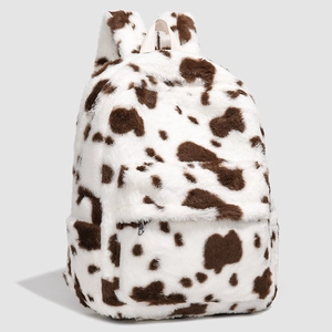 Detail of cow print plush backpack featuring soft faux fur texture and front zipper pocket
