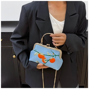Détail d'un sac à main bleu brodé avec motifs de kaki et poignée en métal doré au style rétro