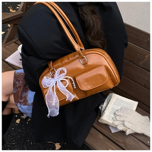 Brown vintage faux leather tote bag with lace bow and pearl chain on a park bench