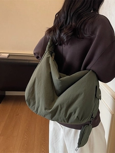 Große armeegrüne Umhängetasche aus Nylon mit Mini-Beutel in lässiger Innenraum-Umgebung