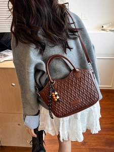 Deep brown quilted bucket bag shown worn crossbody over the shoulder for size reference