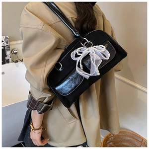 Detail of black underarm bag featuring a white mesh bow and elegant pearl charm detail