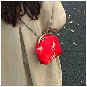 Detail of red brocade bag with bamboo pattern and vintage metal chain in a scenic setting