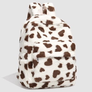 Close-up of fluffy white faux fur backpack with brown heart-shaped cow pattern detail