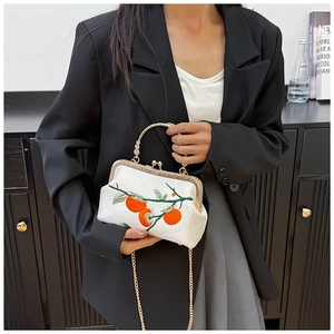 Gros plan d'un sac beige avec broderie de kakis et poignée en métal doré chic