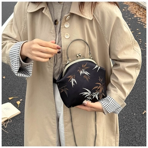 Detail of vintage bamboo print crossbody bag with bronze handle on autumn road background