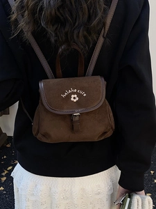 Retro dark brown matte bucket backpack with white floral embroidery worn by a model